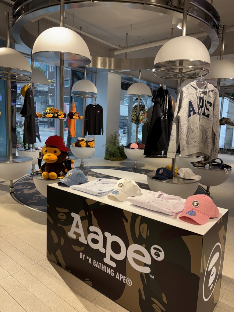 AAPE BY A BATHING APE 聖水ポップアップ店内 AAPEカモフラージュ柄のディスプレイカウンター キャップ・パーカー・BABY MILOぬいぐるみが並ぶストリートファッションスペース
