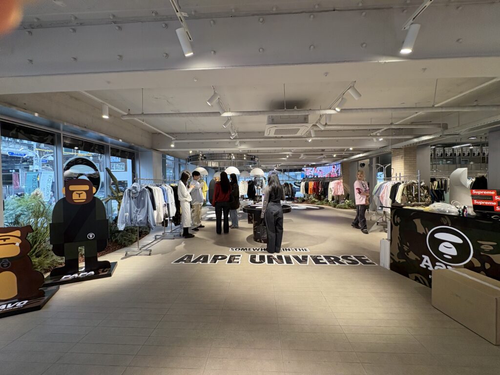 AAPE BY A BATHING APE 聖水EQL GROVEポップアップ 店内全景 AAPE UNIVERSEロゴの床とAAPE MANオブジェ 限定アイテムが並ぶストリートファッションイベント